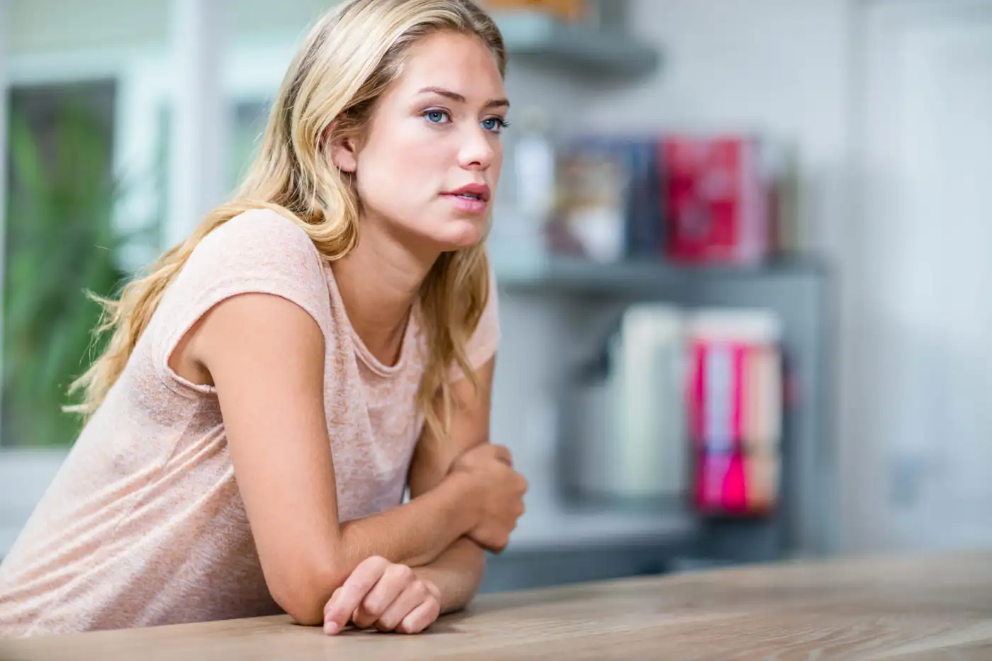 A woman sitting at a kitchen table looking away
