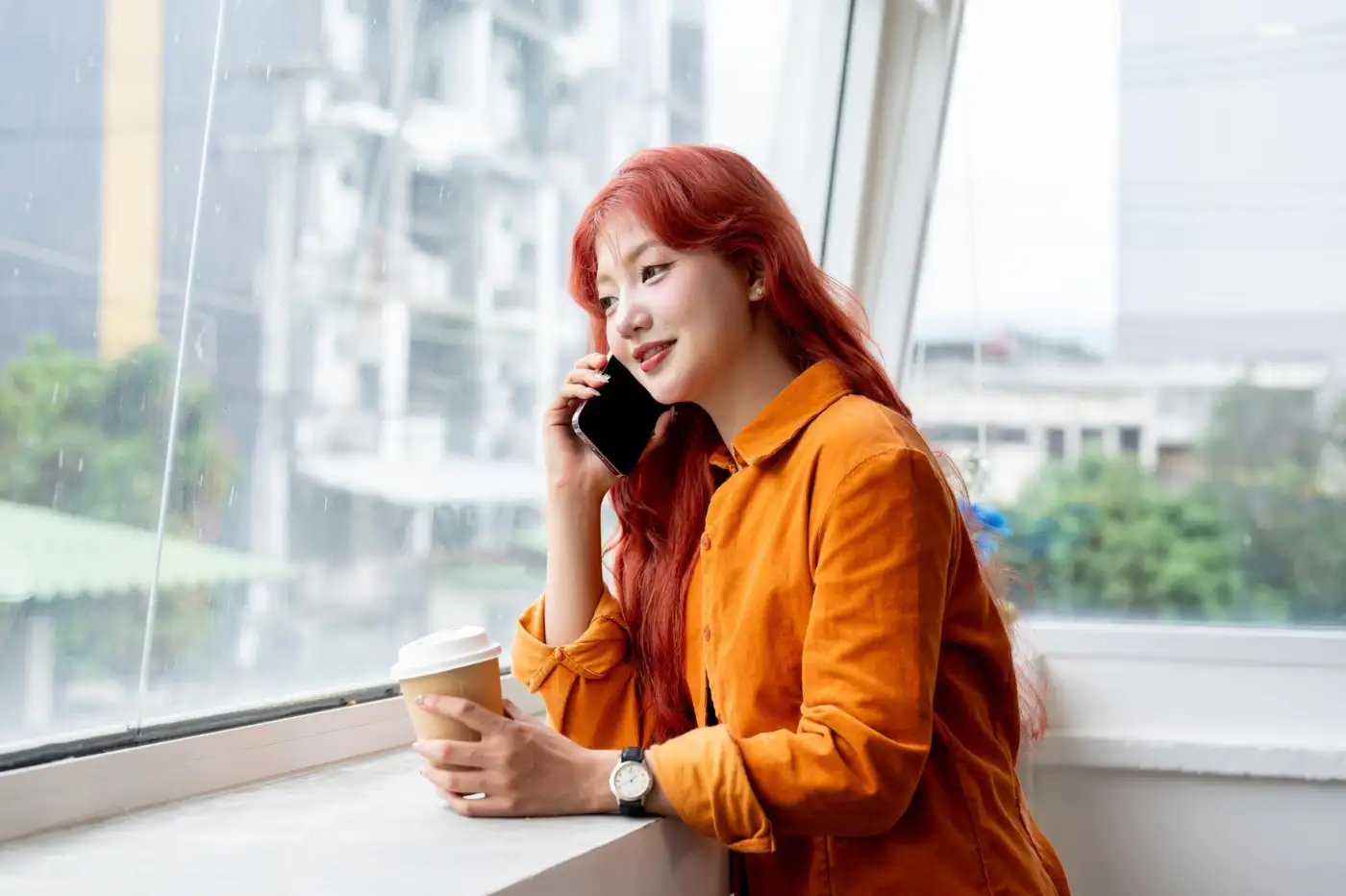 A woman standing by a window talking on her phone