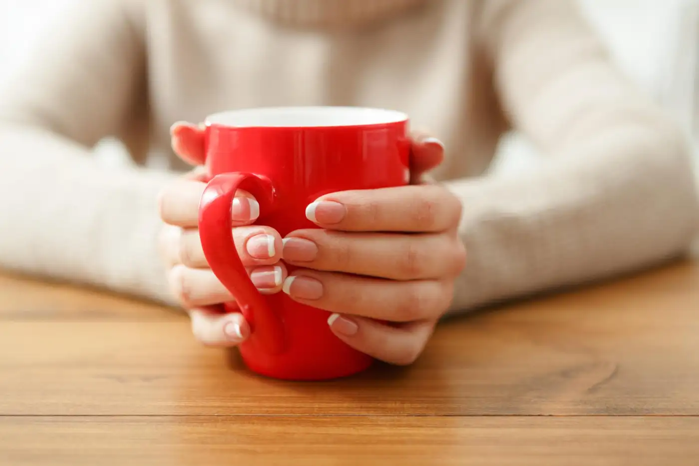 A pair of hands wrapped around a red mug
