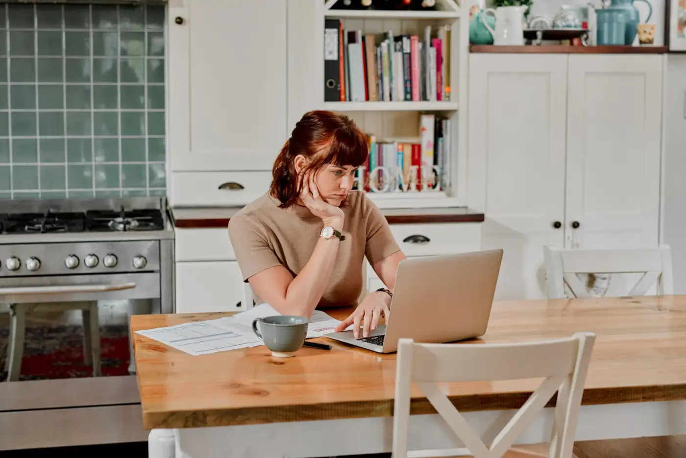 A woman looking over paperwork at her kitchen table