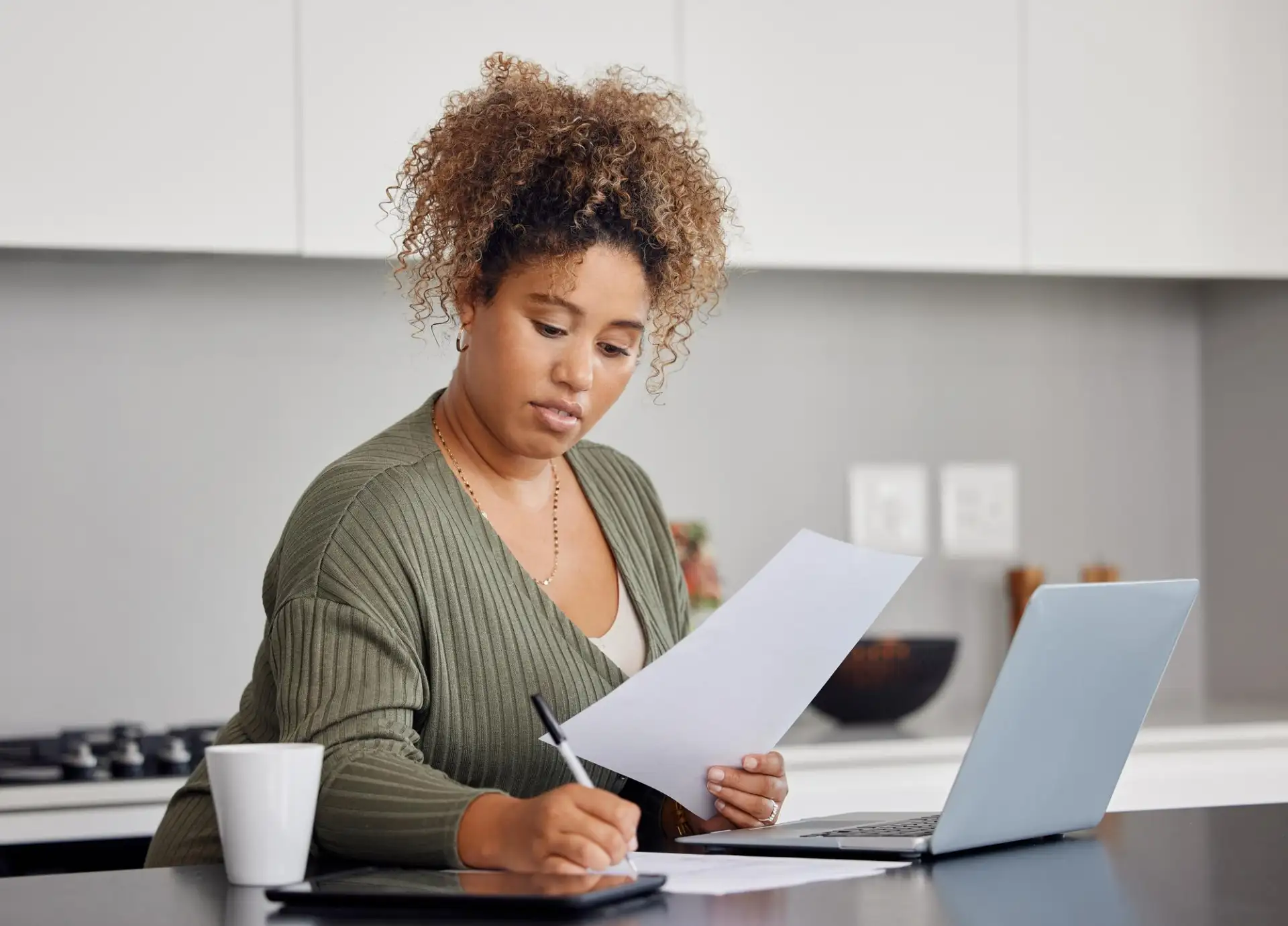 Someone filling in a form at a kitchen table