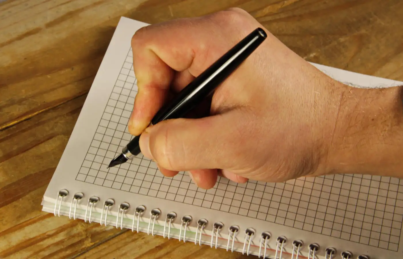 A hand writing in a spiral notebook