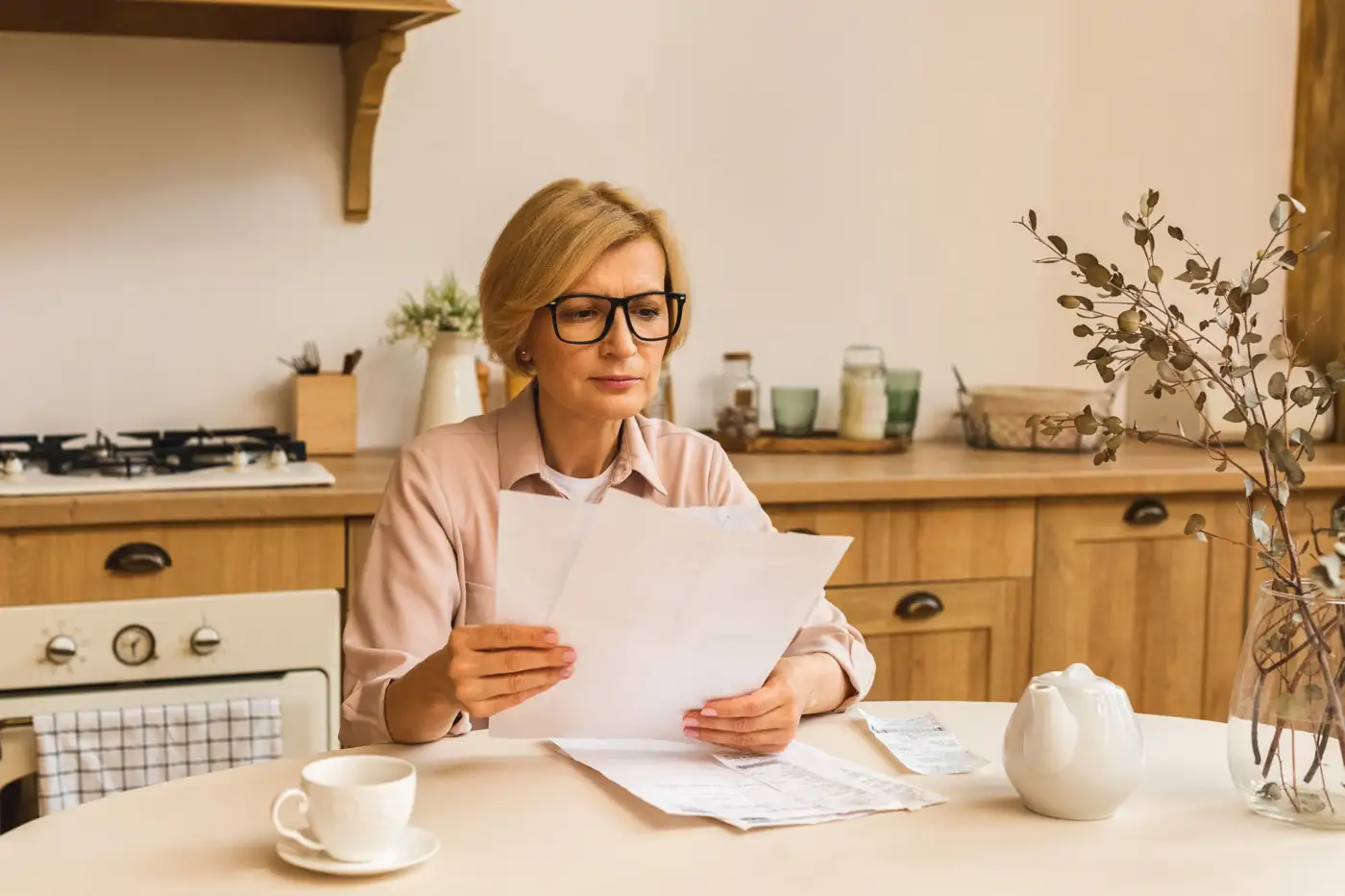 A woman reading a letter at her kitchen table
