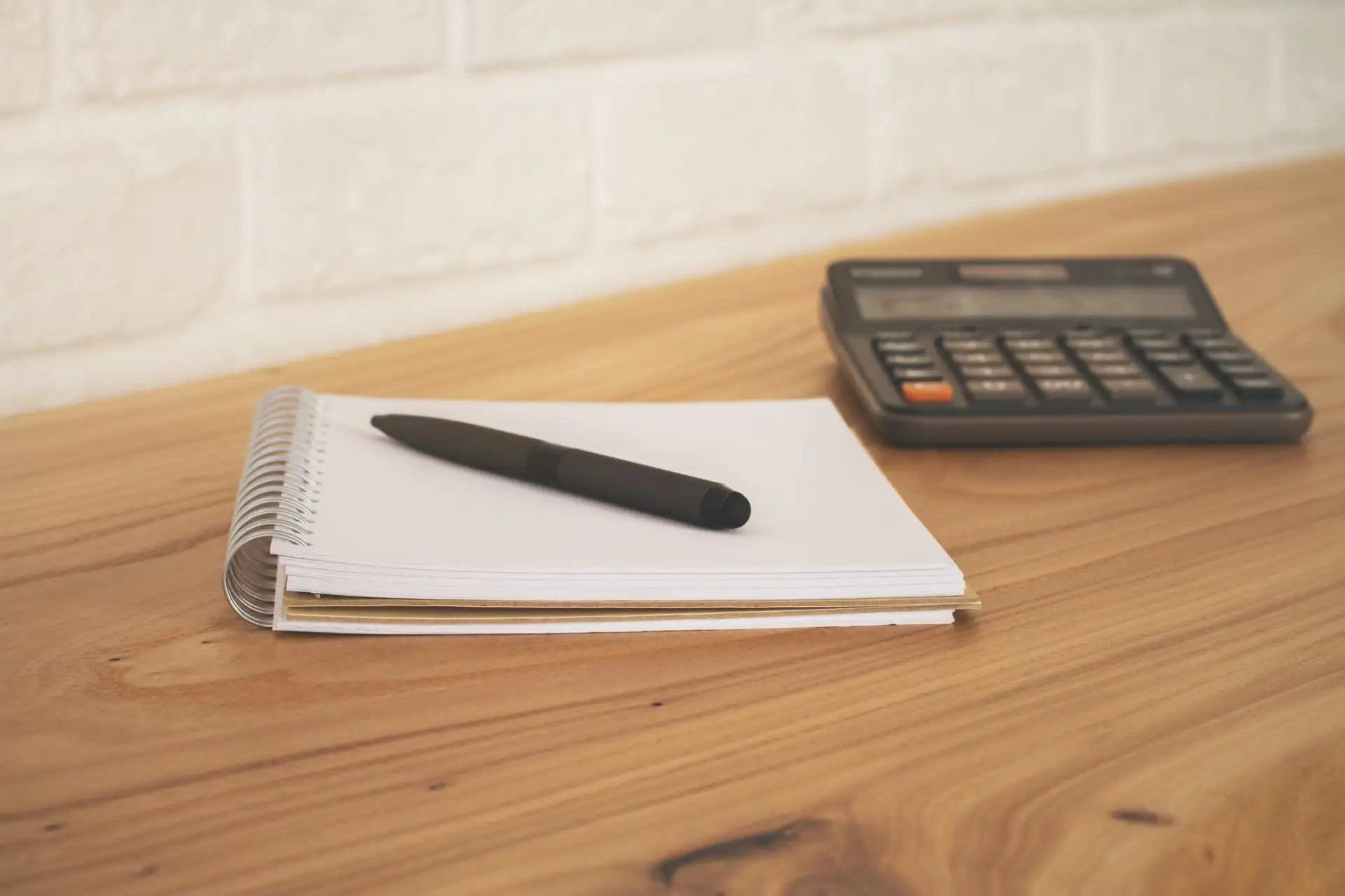 A notepad and pen beside a mobile phone on a kitchen worktop