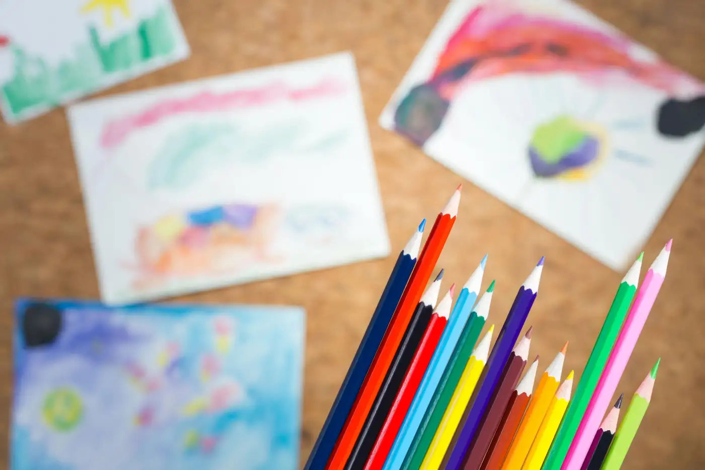 Children's drawings and coloured pencils on a table
