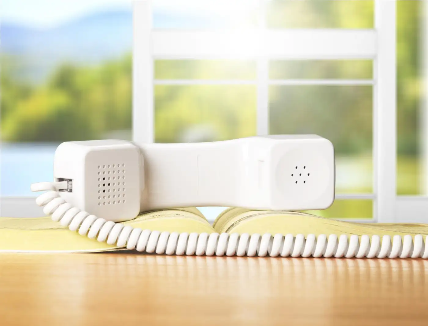 A white corded telephone handset resting on a windowsill