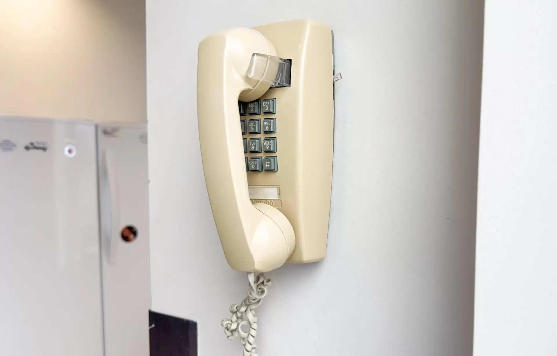A landline handset on a wall-mounted phone