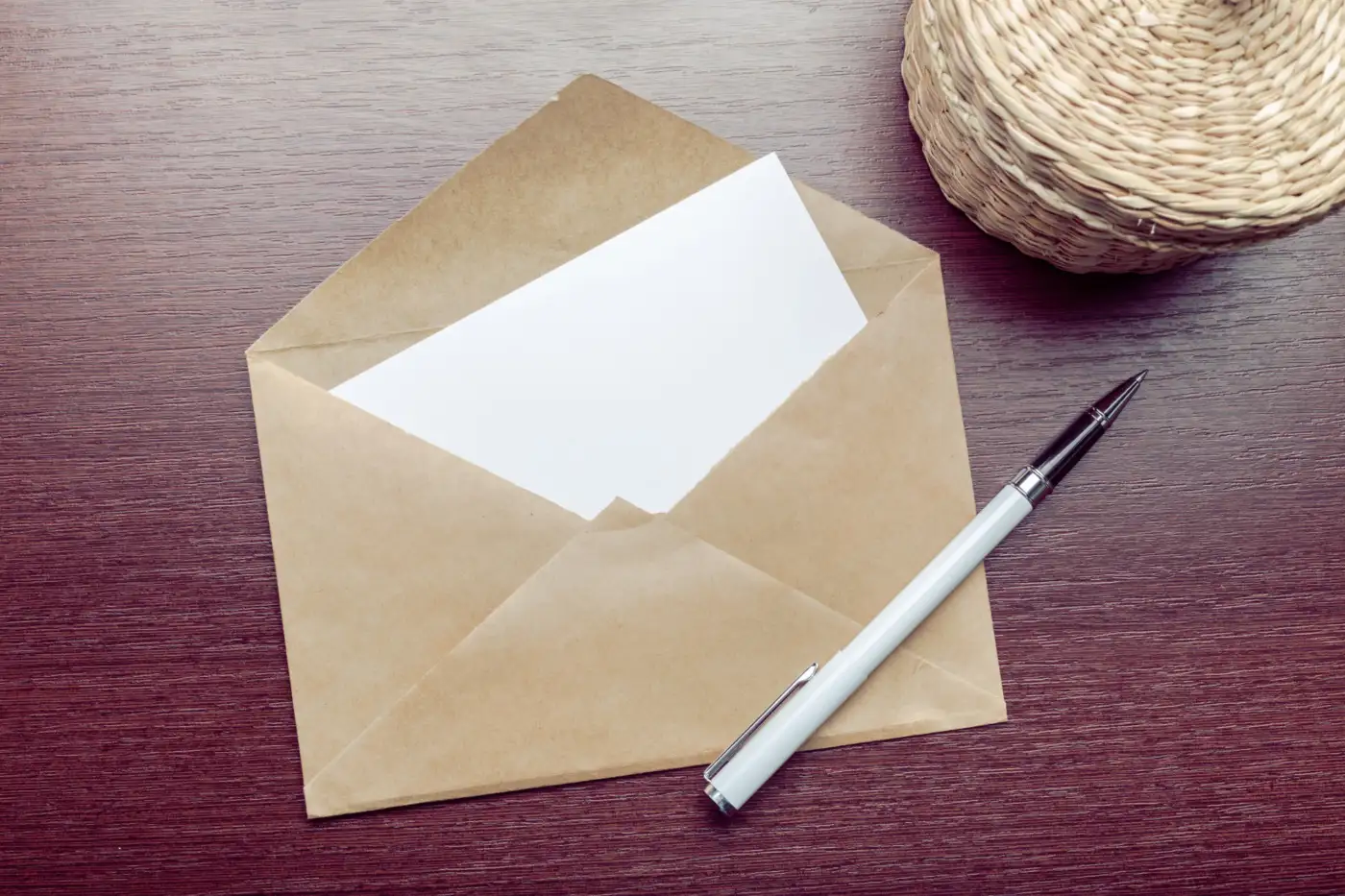 A brown envelope with a card and a pen on a table