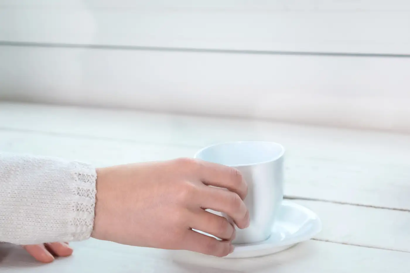 A hand holding a cup and saucer