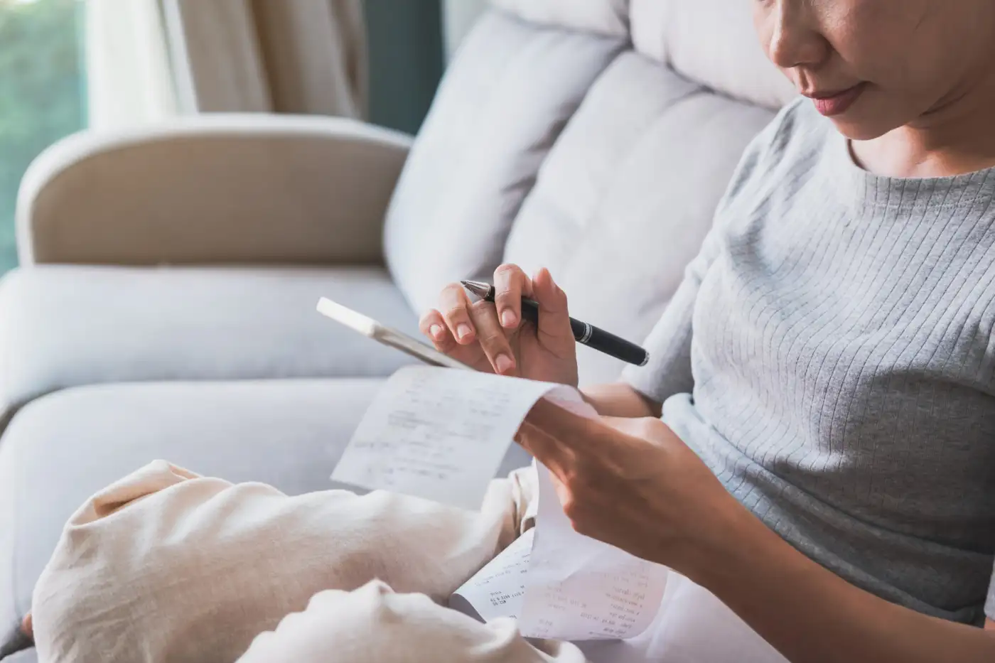 A woman at home checking a bill against her phone