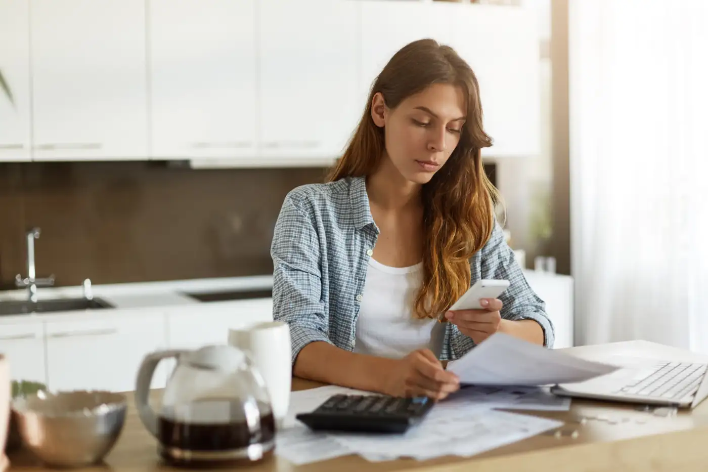 A woman going through household paperwork at her kitchen table