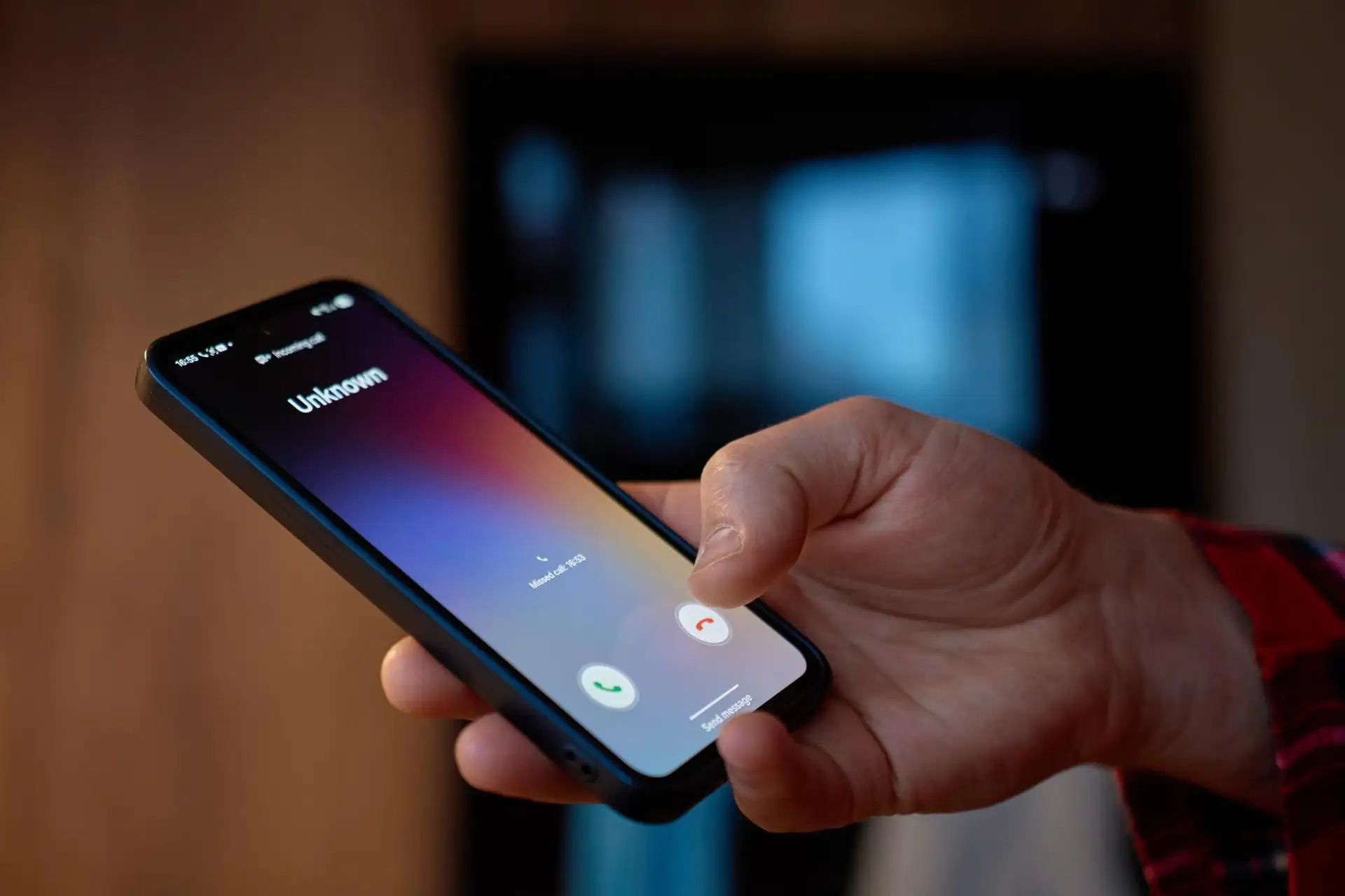 A hand holding a mobile phone showing an incoming call from an unknown number