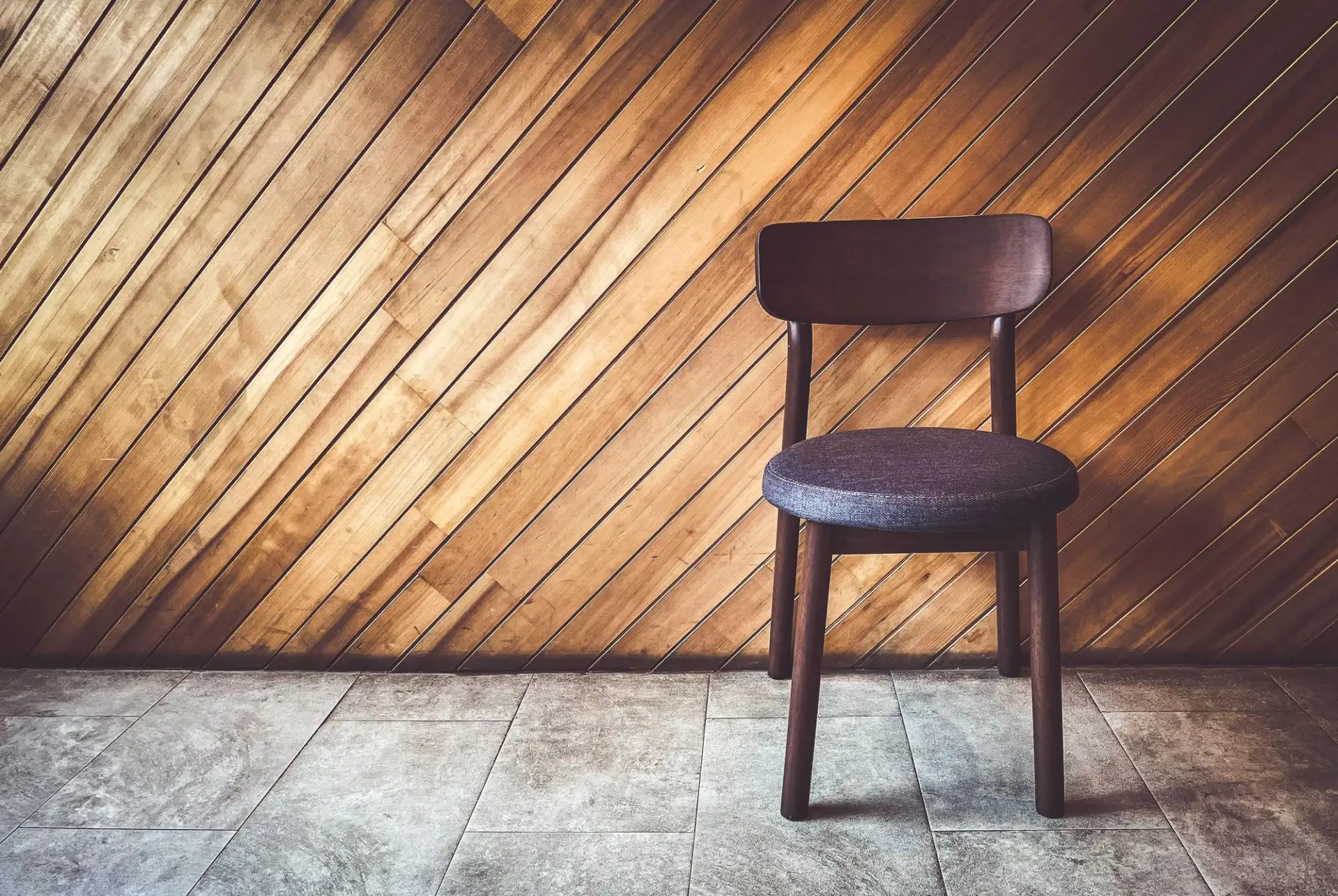 A single empty wooden chair against a wall