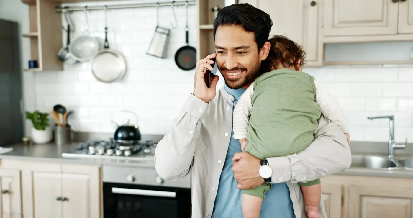 Father on a phone call with his baby in the kitchen