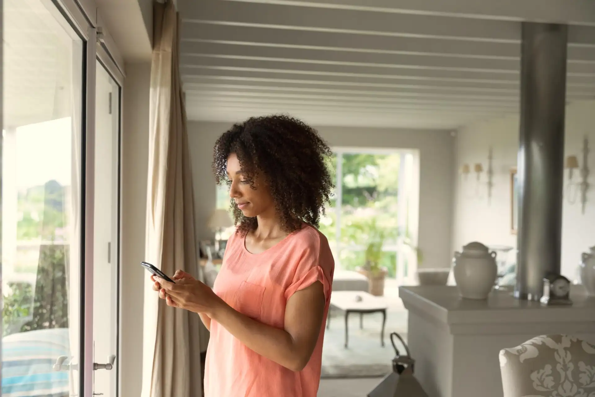 A woman standing in a home kitchen looking at her phone