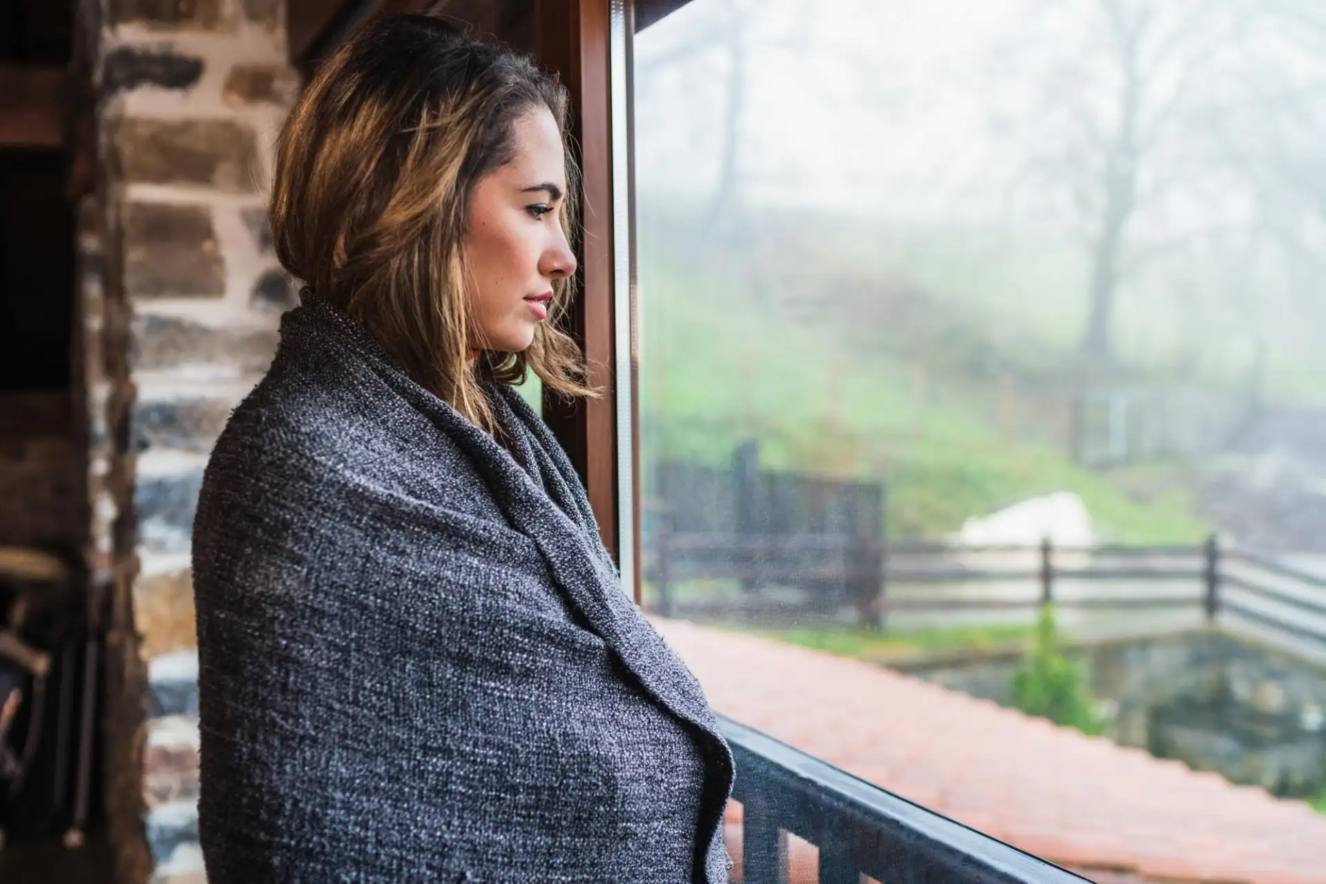A woman looking out of a window across open fields